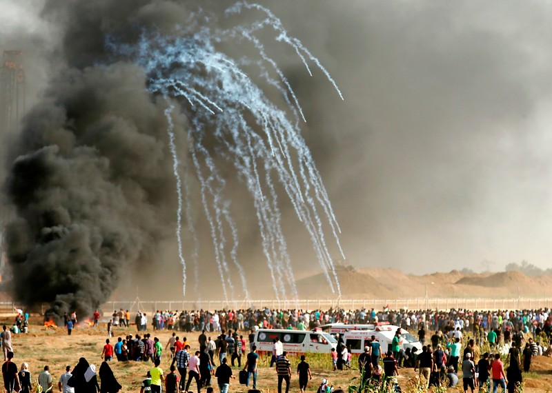 Παλαιστίνιες/οι διαδηλώτριες/ωτές τρέχουν να καλυφθούν μετά την εκτόξευση δακρυγόνων από τις ισραηλινές δυνάμεις. Photo: AFP via Getty Images.AFP μέσω Getty Images.